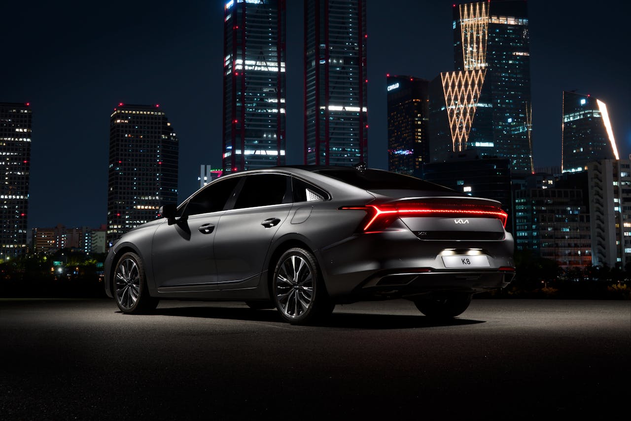 Black Modern Car Standing Illuminated and Big City in Background