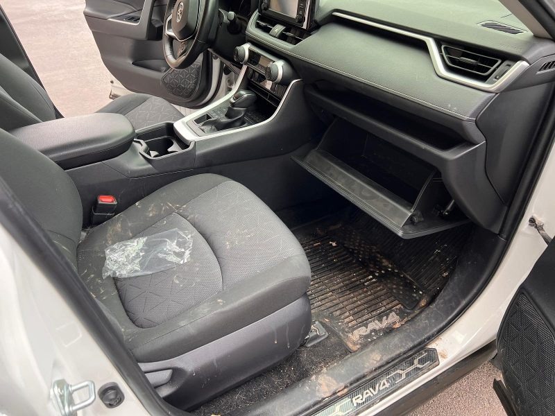Before detailing: Interior of a RAV4 showing heavy dirt, stains, and clutter, with the seats, floor mats, and dashboard in need of thorough cleaning and restoration to bring back a fresh, well-maintained appearance